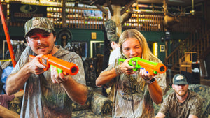 A couple competes with each other playing Big Buck Hunter.
